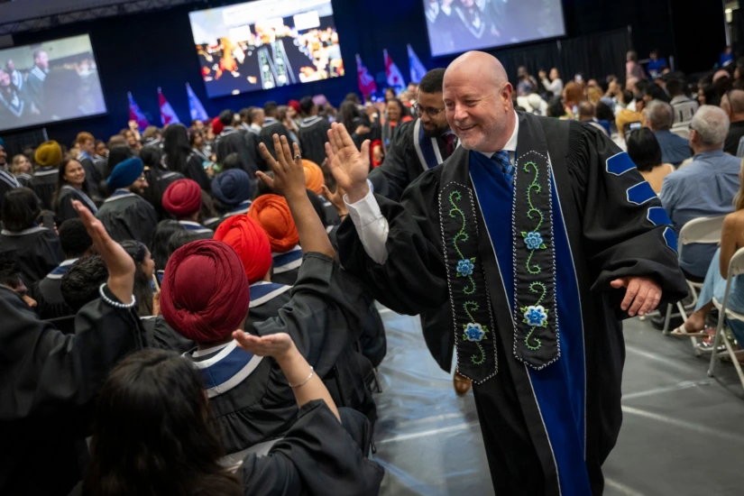 President Sean Kennedy high-fives graduates as convocation concludes.